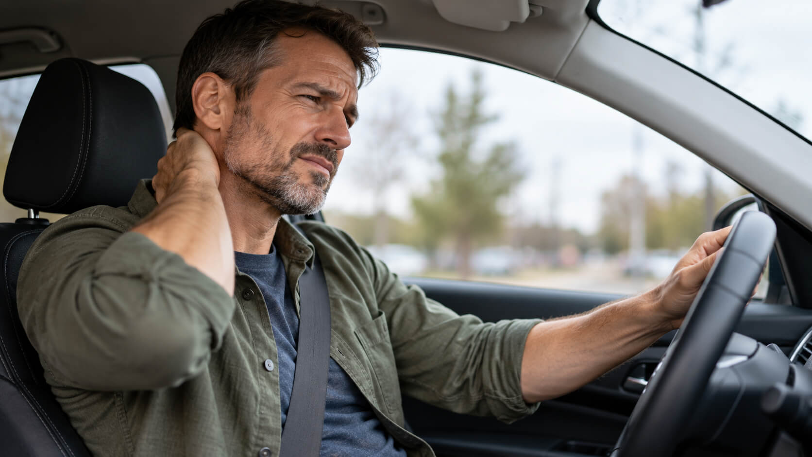 Driver holding his neck in pain after a car accident